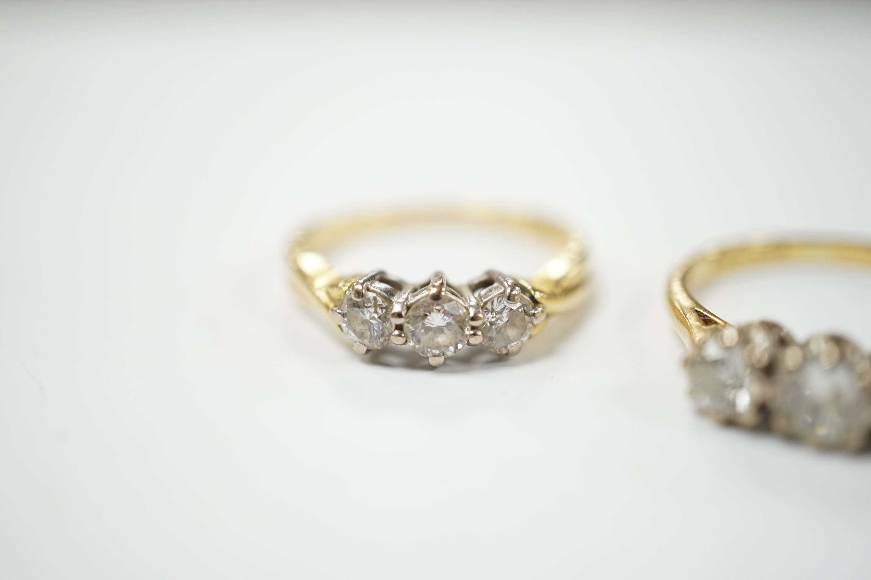 An 18ct gold three stone diamond ring, size M, and a similar ring of larger size, size P, gross 6.2 grams